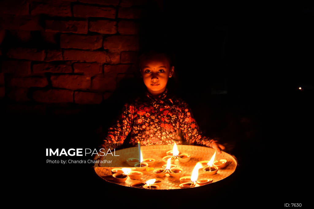 Child lighting a clay oil lamp (diyo) during Tihar in Nepal