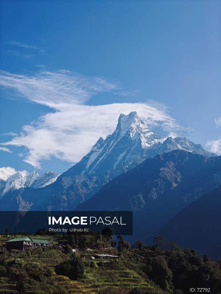 Machhapuchhre (Fishtail) peak under a clear blue sky with wispy clouds