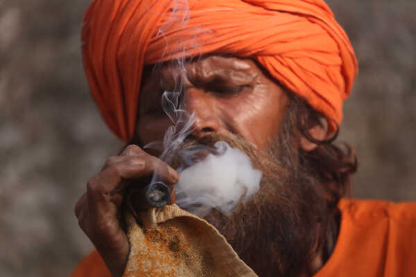 A sadhu participates in Shivaratri rituals while smoking a chillum at the Pashupatinath Temple premises, 2026.
