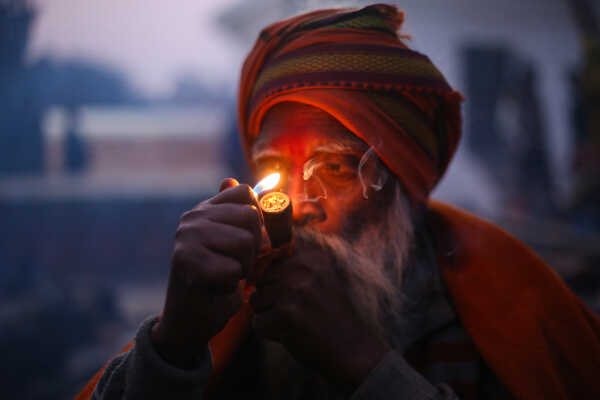 A sadhu participates in Shivaratri rituals while smoking a chillum at the Pashupatinath Temple premises, 2026.