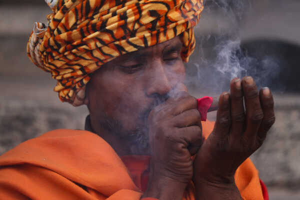 A sadhu participates in Shivaratri rituals while smoking a chillum at the Pashupatinath Temple premises, 2026.