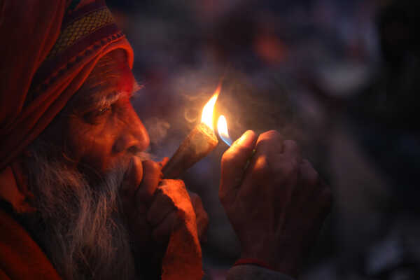 A sadhu participates in Shivaratri rituals while smoking a chillum at the Pashupatinath Temple premises, 2026.